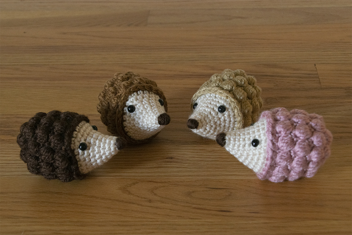 Four hedgehog amigurumi facing each other in a semi circle
